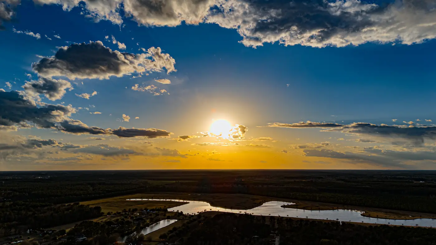 Drone view of the sun setting over a winding river and wetlands near Moncks Corner, SC